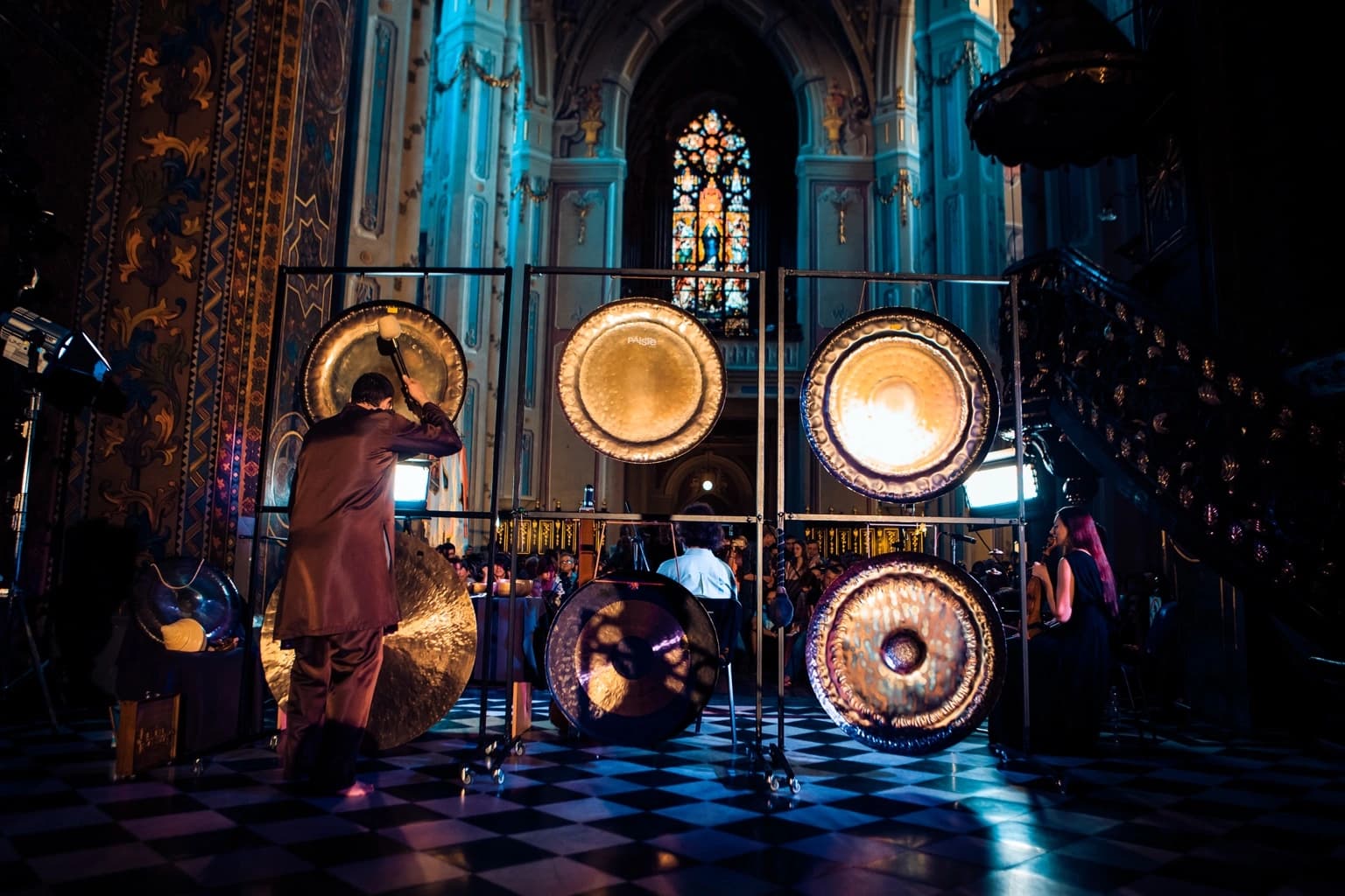 Gong master performing before an array of illuminated gongs